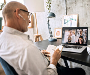 Business man writing information while listening to online call