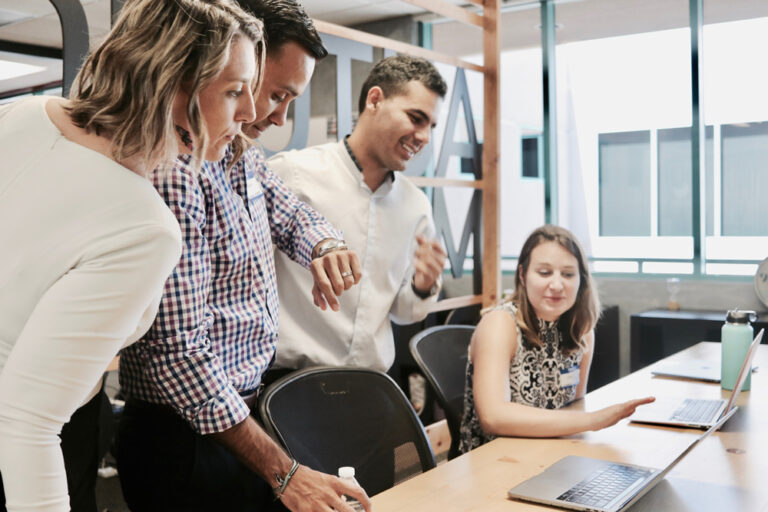 Happy young business people looking at laptop